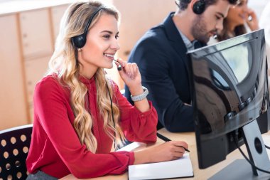 selective focus of smiling call center operator working in office clipart