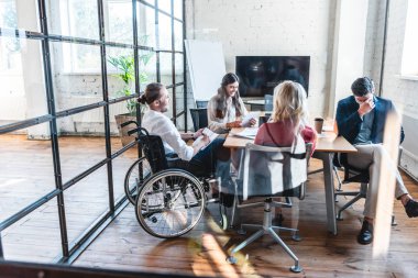 young businessman in wheelchair working with colleagues in office 