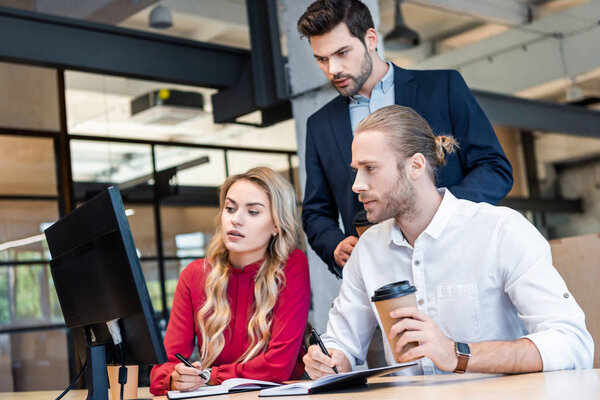 business team working on business project together at workplace with notebooks in office