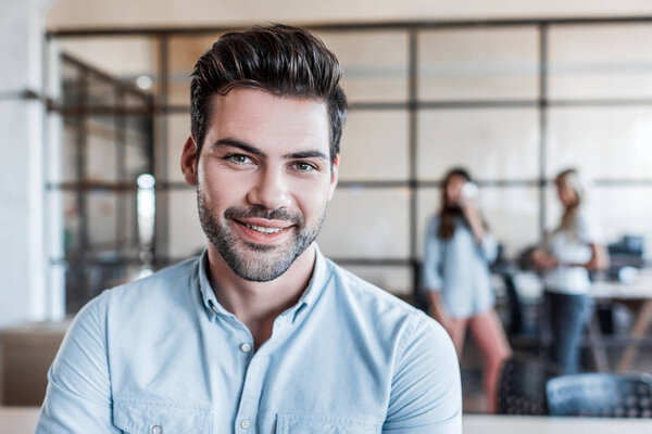 portrait of handsome young businessman smiling at camera in office