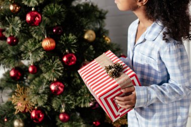Afro-Amerikan çocuk Noel hediye kutusu evde tutan pijama kırpılmış görüntü