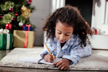 çok güzel Afro-Amerikan çocuk yerde yatıyor ve bir şey için dizüstü evde, Noel kavramı yazma pijama