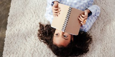çok güzel Afro-Amerikan çocuk halı üzerinde yalan ve defterini odada suratla kapsayan pijama üstten görünüm