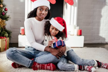 santa şapka kucaklama kız evde hediye ile Afrika kökenli Amerikalı anne