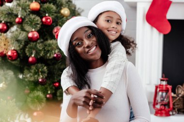 santa claus şapka sarılma anne evde küçük Afro-Amerikan kızı