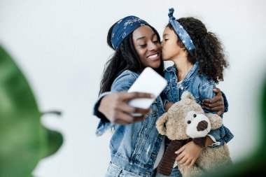 Afrikalı-Amerikalı kadın selfie smartphone yanağını öpmeye kızı süre taking 
