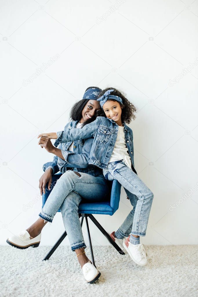 smiling african american daughter near mother in chair at home