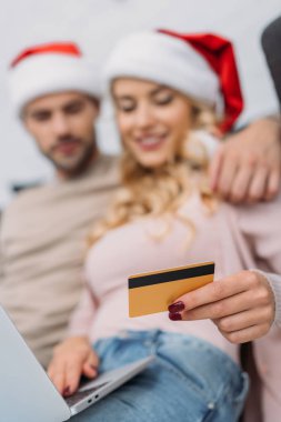 Noel Baba şapkaları alışveriş online kredi kartı ve evde laptop ile çiftin seçici odak