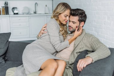 Onun erkek arkadaşı ona evde kanepede otururken kucaklayan güzel genç kadın