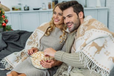 Genç çift evde film izlerken patlamış mısır ile gülümseyen