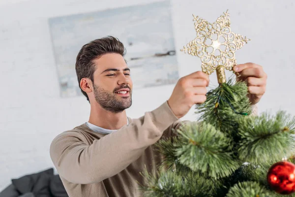 Smiling Handsome Man Decorating Christmas Tree Star Home — Stock Photo, Image