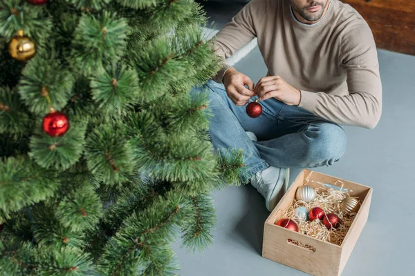 Imagem Cortada Homem Decorando Árvore Natal Com Bugigangas Sentado Chão — Fotografia de Stock