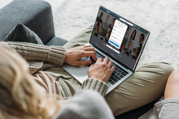 cropped shot of couple using laptop with linkedin website on screen on couch at home