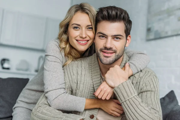 Feliz Joven Mujer Abrazando Novio Sofá Casa Mirando Cámara — Foto de Stock