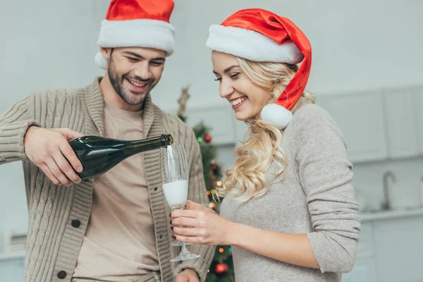 Happy Young Couple Pouring Champagne Glasses Front Christmas Tree Home — Stock Photo, Image