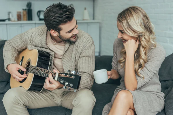 Jovem Feliz Tocando Guitarra Para Namorada Casa Enquanto Ela Está — Fotografia de Stock