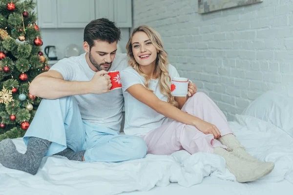 Feliz Jovem Casal Com Xícaras Cacau Sentado Cama Casa Natal — Fotografia de Stock