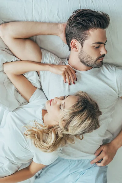 顶视图的美丽年轻的夫妇在家里的床上睡在一起 — 图库照片
