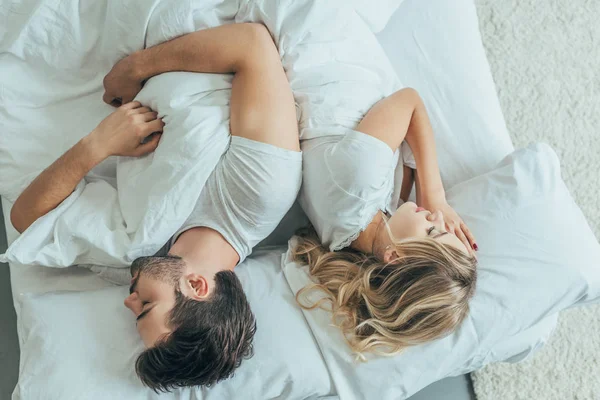 背中合わせに自宅のベッドで一緒に寝て美しい若いカップルの平面図 — ストック写真