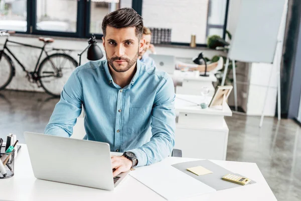 Jovem Empresário Bonito Usando Laptop Olhando Para Câmera Escritório — Fotografia de Stock