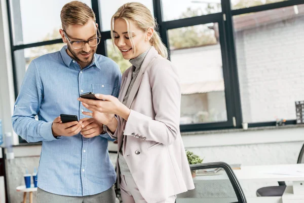 Úsměvem Mladá Spolupracovníky Pomocí Smartphonů Mluví Pracovišti — Stock fotografie