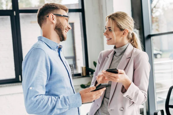 Jóvenes Colegas Negocios Utilizando Teléfonos Inteligentes Sonriendo Entre Oficina — Foto de Stock