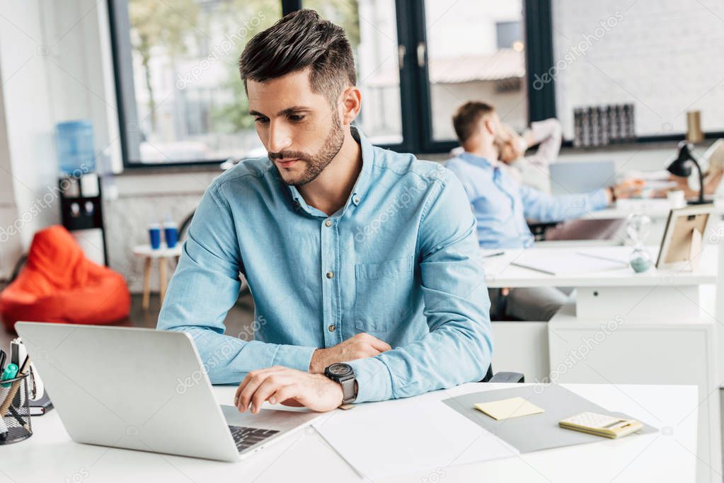 handsome bearded young businessman using laptop at workplace