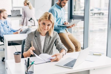 kamera arkasında ofisinde çalışan meslektaşları süre gülümseyen güzel genç iş kadını