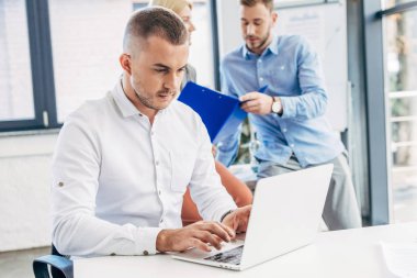 genç işadamı laptop ve meslektaşları arkasında çalışma office kullanarak