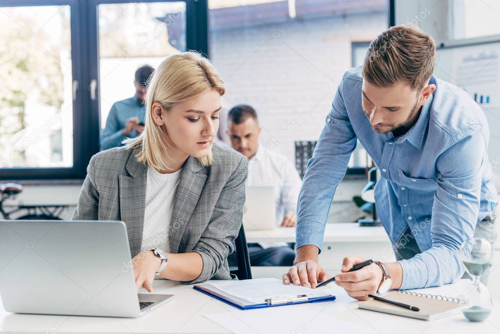 young businessman and businesswoman working with papers and laptop in office