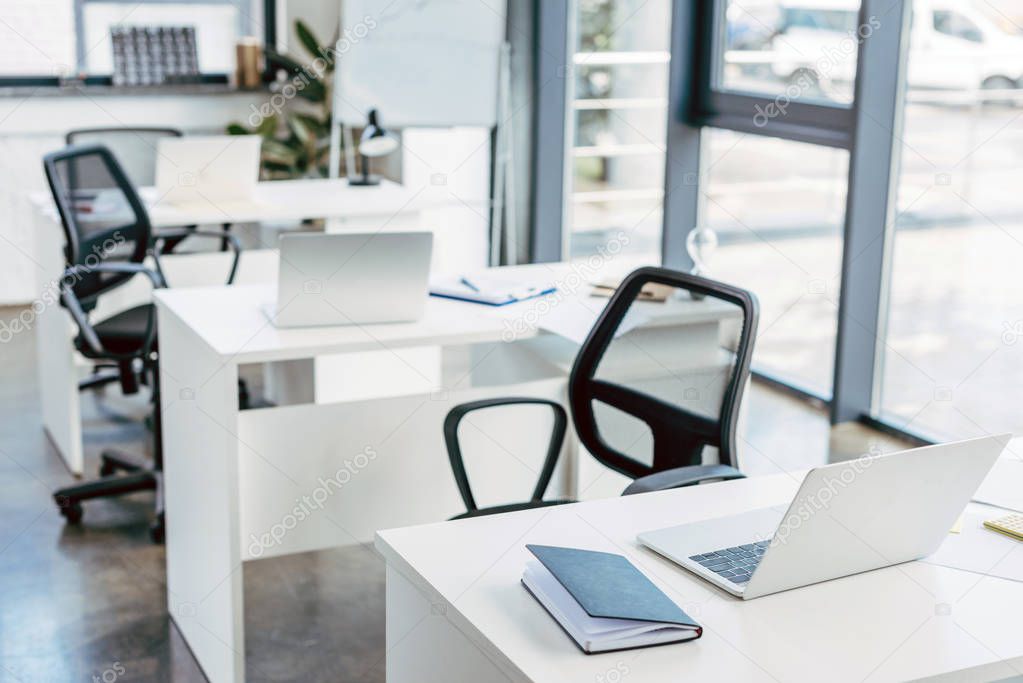 laptop on tables in empty modern office