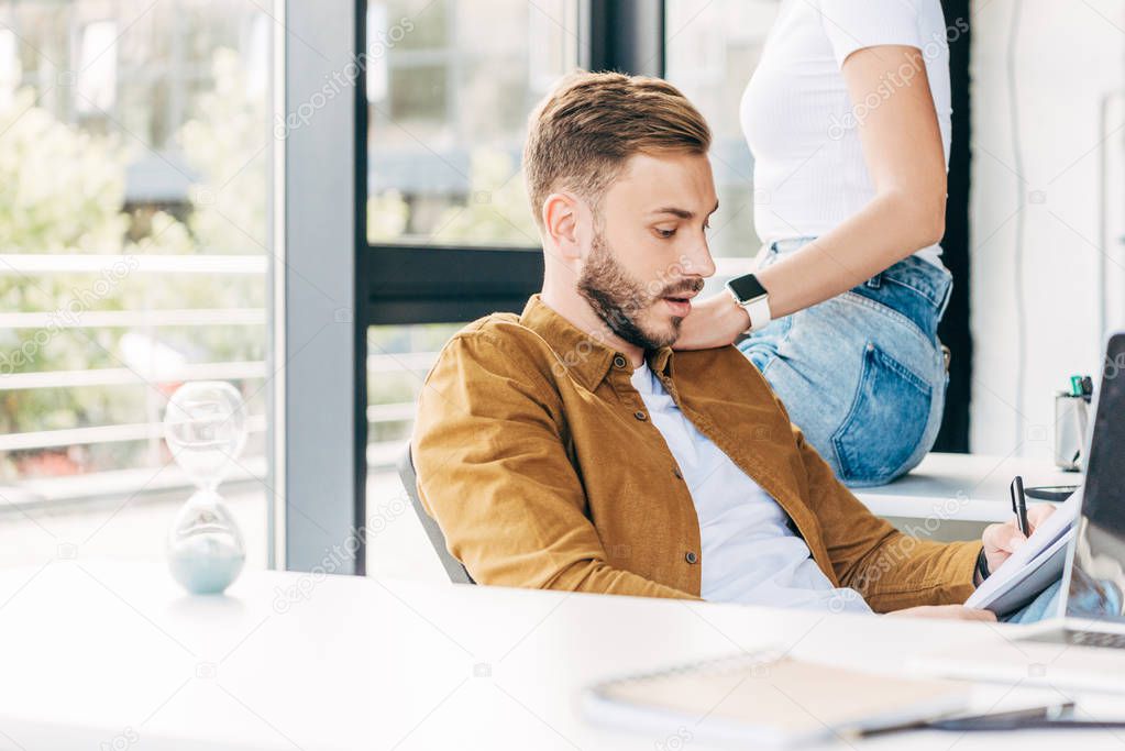 cropped shot of handsome young man and woman flirting while working together at office