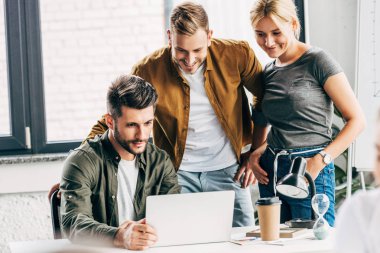 group of young managers working with laptop together at office clipart