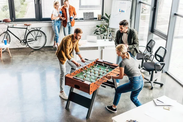 若いカジュアルなビジネスの人々 のオフィスでテーブル サッカーを遊んで 一緒に楽しんでのハイアングル — ストック写真