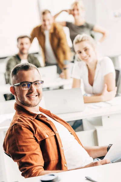 Joven Sonriente Trabajando Oficina Espacio Abierto Mirando Cámara Con Colegas — Foto de Stock