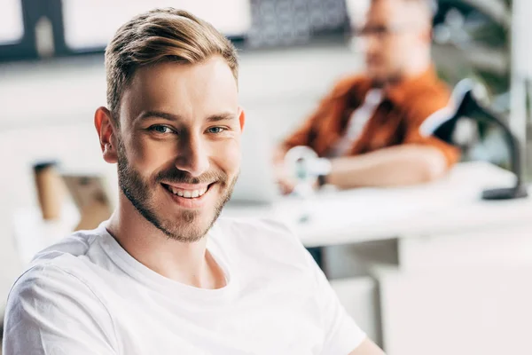 Knappe Jonge Zakenman Kijken Camera Met Collega Zitten Vaag Achtergrond — Stockfoto