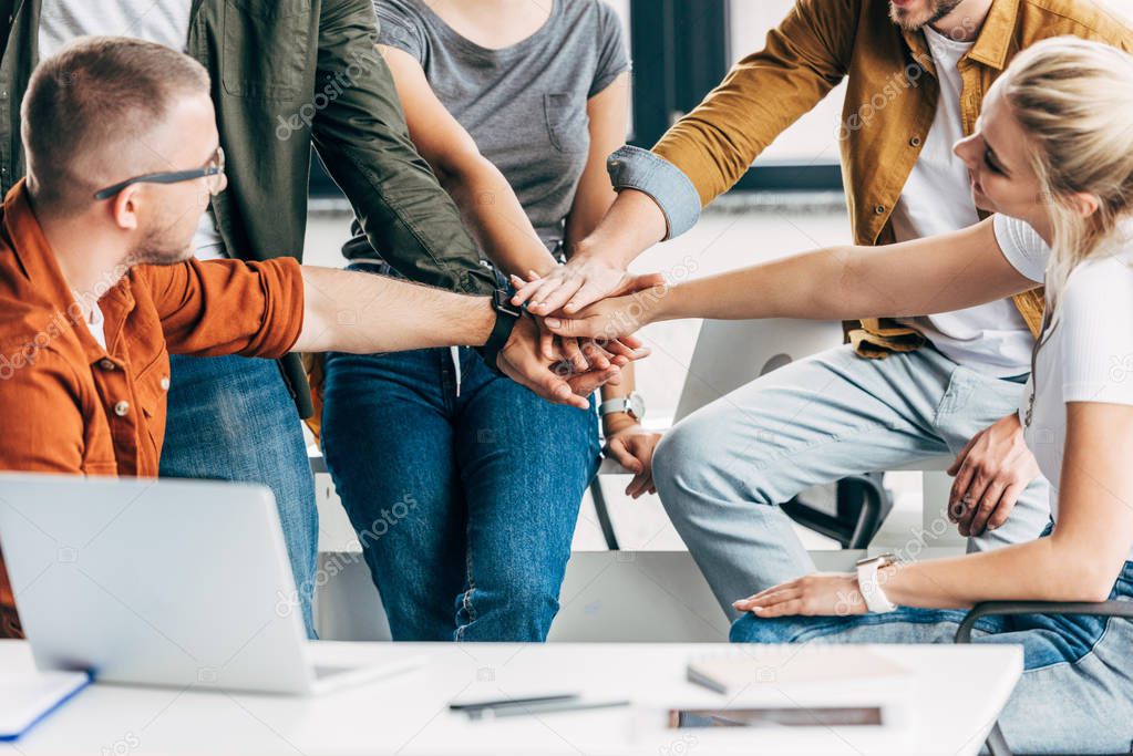 cropped shot of group of young entrepreneurs making team gesture while working on startup together at office