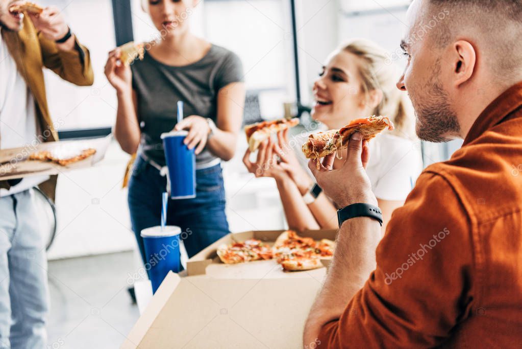 group of happy entrepreneurs having pizza for lunch together while working on startup at office