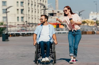 çekici kız bir şey üzerinde sokakta tekerlekli sandalyede yakışıklı erkek işaret