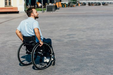 yakışıklı adam tekerlekli sandalye sokakta kullanarak güneş gözlüğü yan görünüm