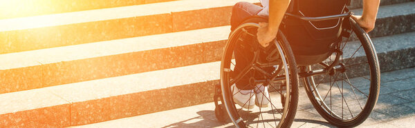 обрезанное изображение инвалида в инвалидной коляске на улице и остановка возле лестницы без пандуса

