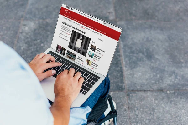 男子在轮椅上的裁剪图像使用笔记本电脑与 Bbc 新闻网站在街道上 — 图库照片