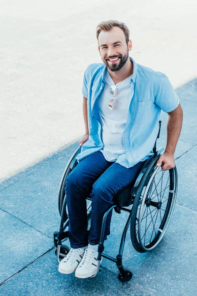 高角度视图的微笑英俊的人使用轮椅在街道上 看着相机 — 图库照片