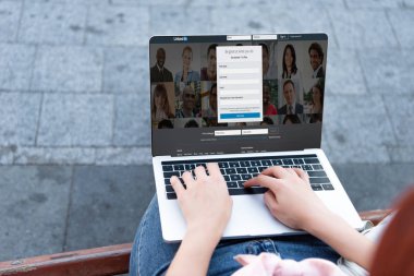 kadının sokakta yüklü LinkedIn sayfa ile dizüstü bilgisayar kullanarak kırpılmış görüntü