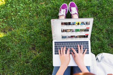 cropped image of woman using laptop with loaded youtube page in park