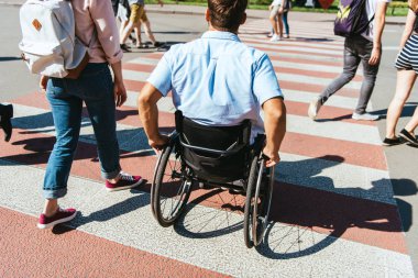 back view of boyfriend in wheelchair and girlfriend crossing crosswalk in city clipart