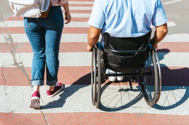 cropped image of boyfriend in wheelchair and girlfriend crossing crosswalk in city clipart