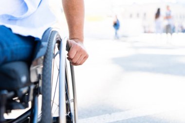 cropped image of disabled man using wheelchair on street clipart