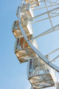 cabins of observation wheel against blue sky in amusement park clipart