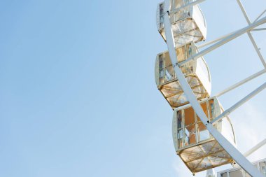 cabins of ferris wheel against blue sky in amusement park clipart